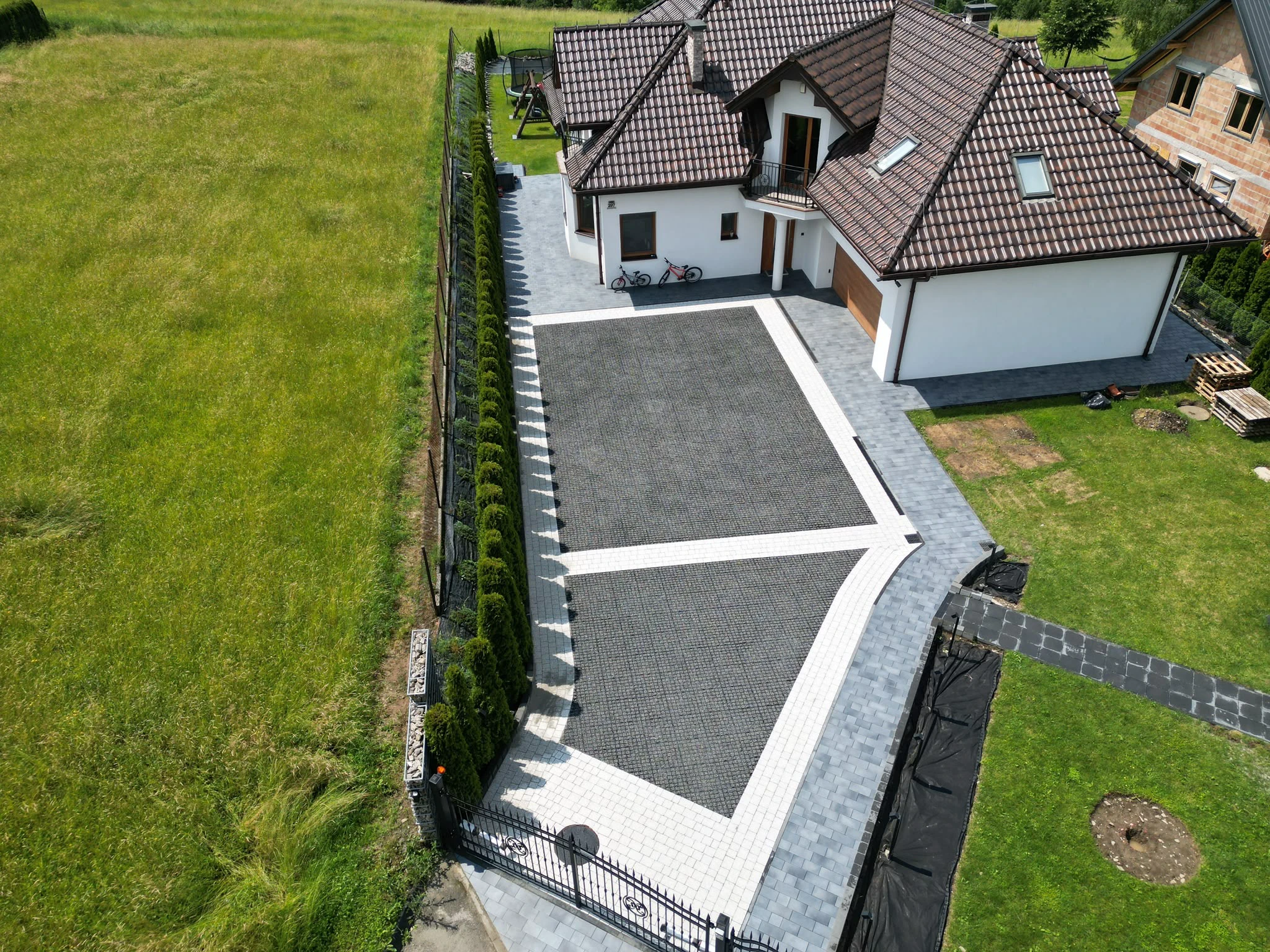Podjazdy z kostki brukowej, nowoczesny podjazd z szarej kostki z białym obramowaniem przy domu