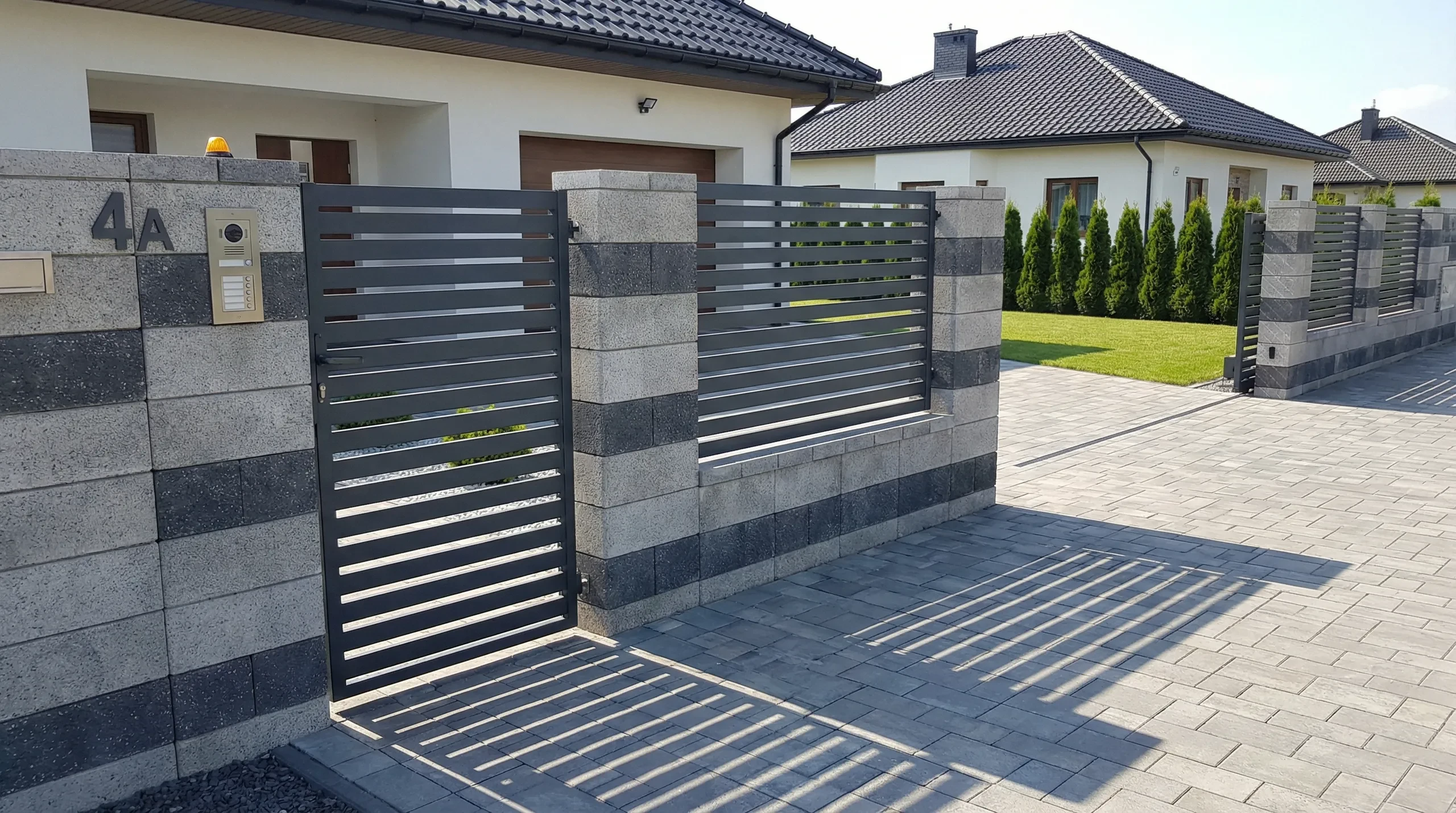 Podjazdy z kostki brukowej przy nowoczesnym ogrodzeniu panelowym z furtką przed domem