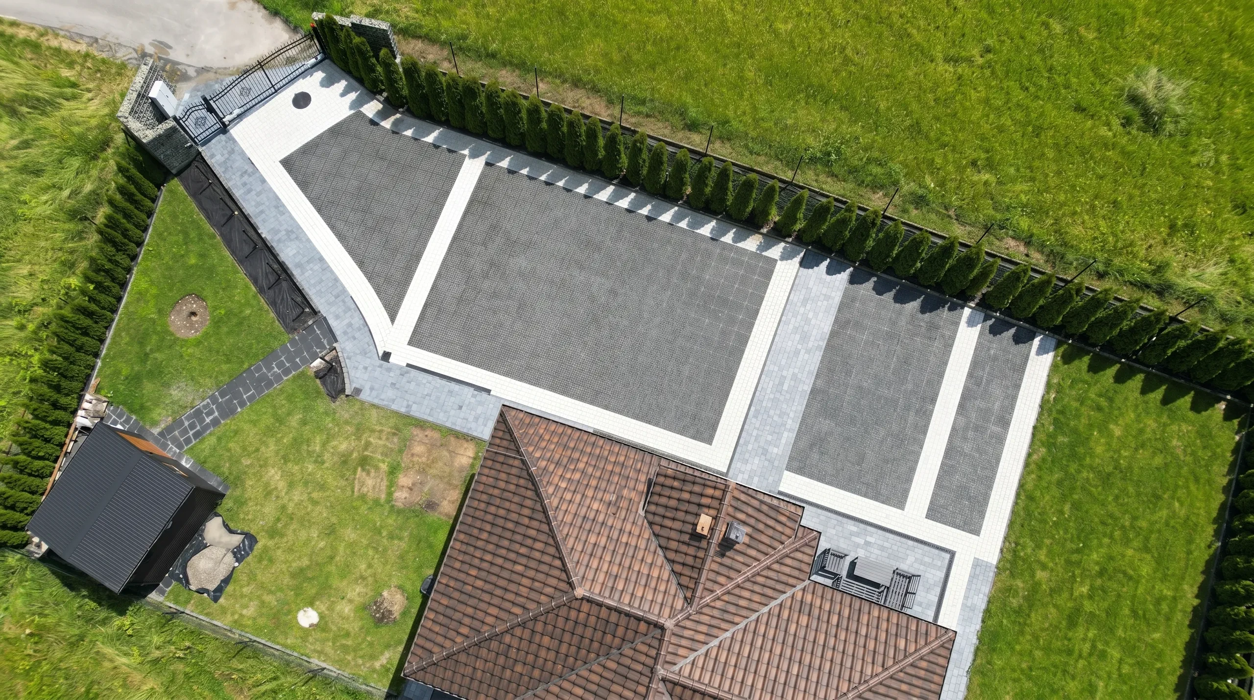 Podjazd z kostki brukowej z szarą nawierzchnią i jasnymi obrzeżami, widok z góry