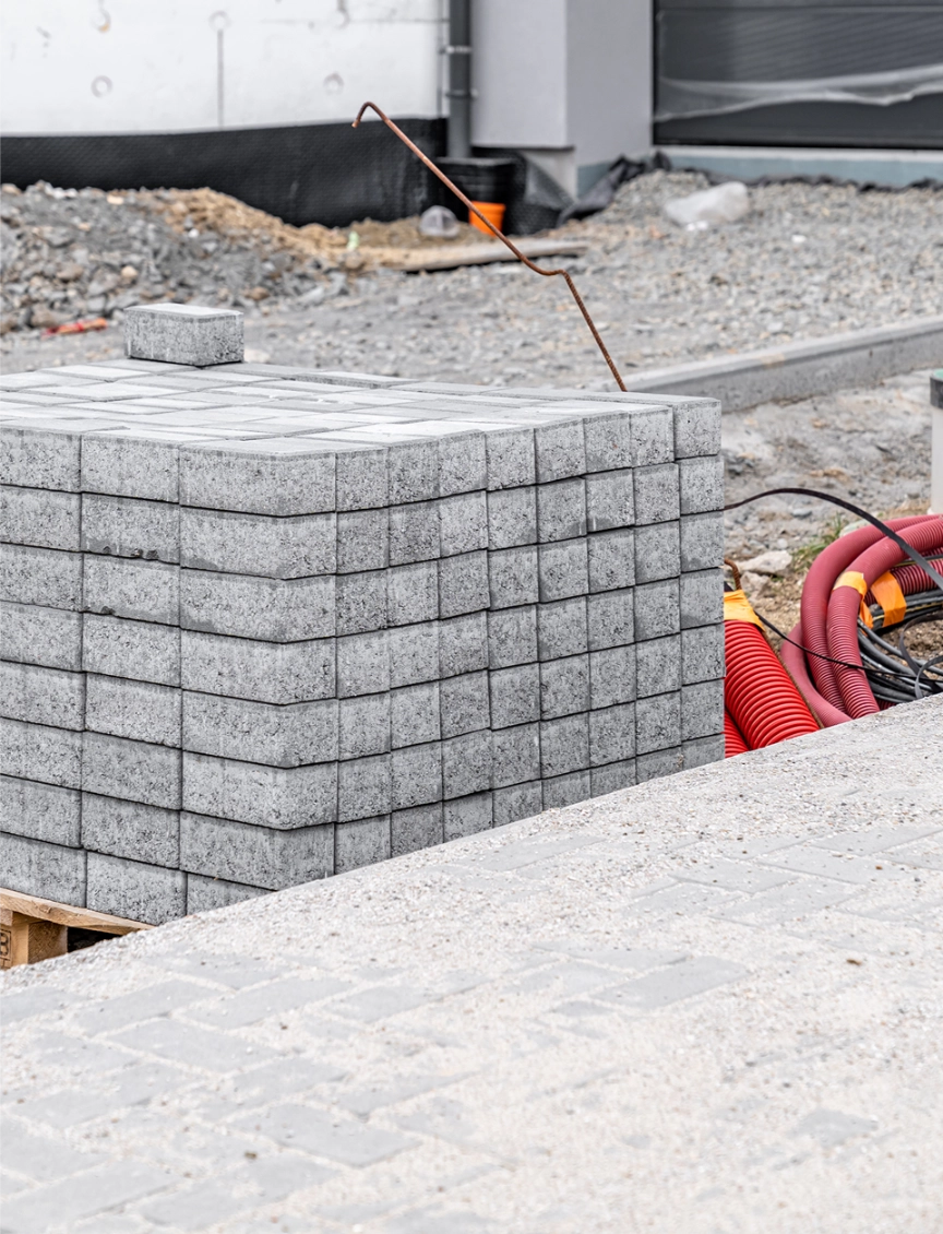 Stos kostki betonowej na niwelowanym terenie z kablem instalacyjnym przed układaniem kostki betonowej